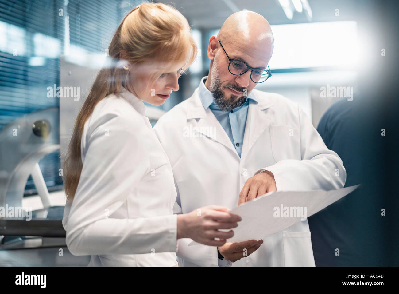 Two technicians wearing lab coats looking at plan Stock Photo