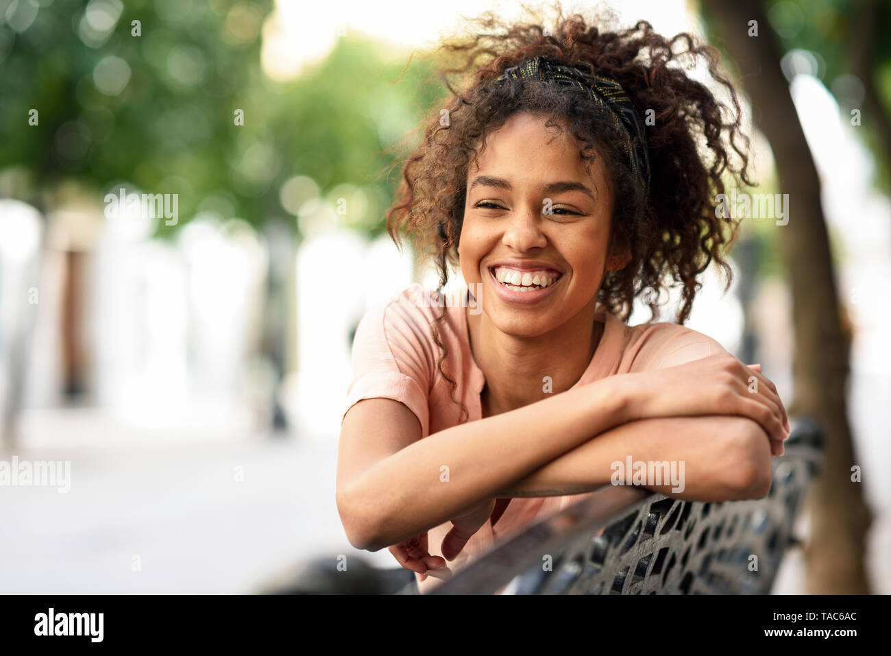 Portrait of happy young woman sitting on a bench Stock Photo - Alamy