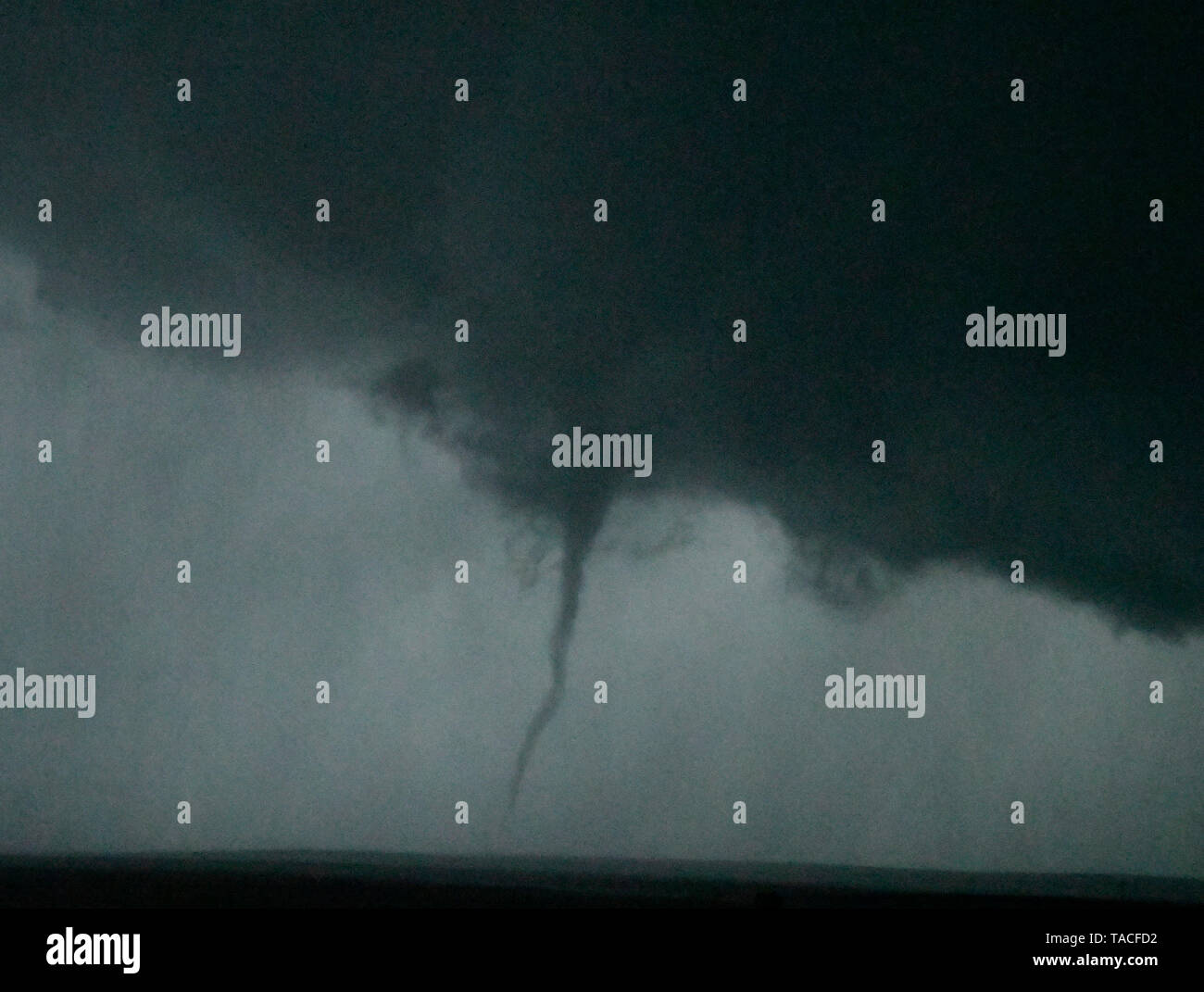 A small tornado is seen from storm cells crossing over the town of