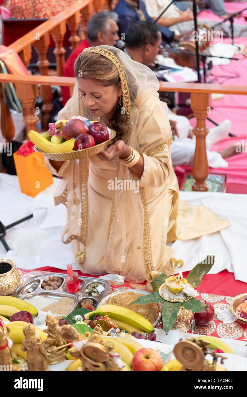 A devout Hindu worshipper making an offering to the deities at a temple in Jamaica, Queens, New York Stock Photo