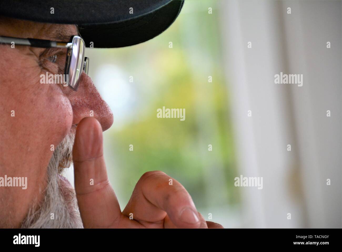 Senior man making a point with his finger and talking to friends with glasses very closeup face and ball cap Stock Photo