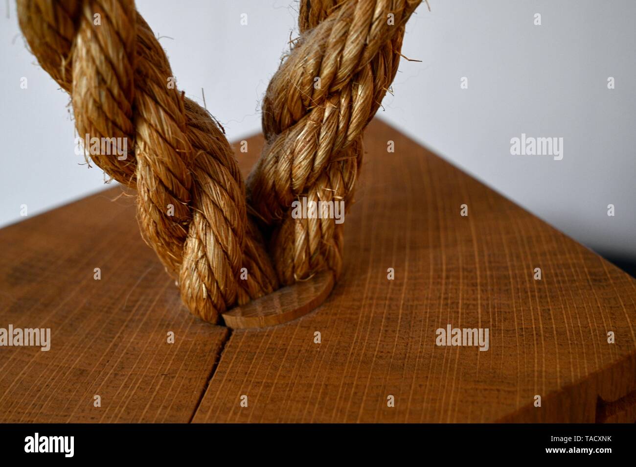 A highly textured loop of fishing rope set in a wooden buoy or floatation device on a light interior. Stock Photo