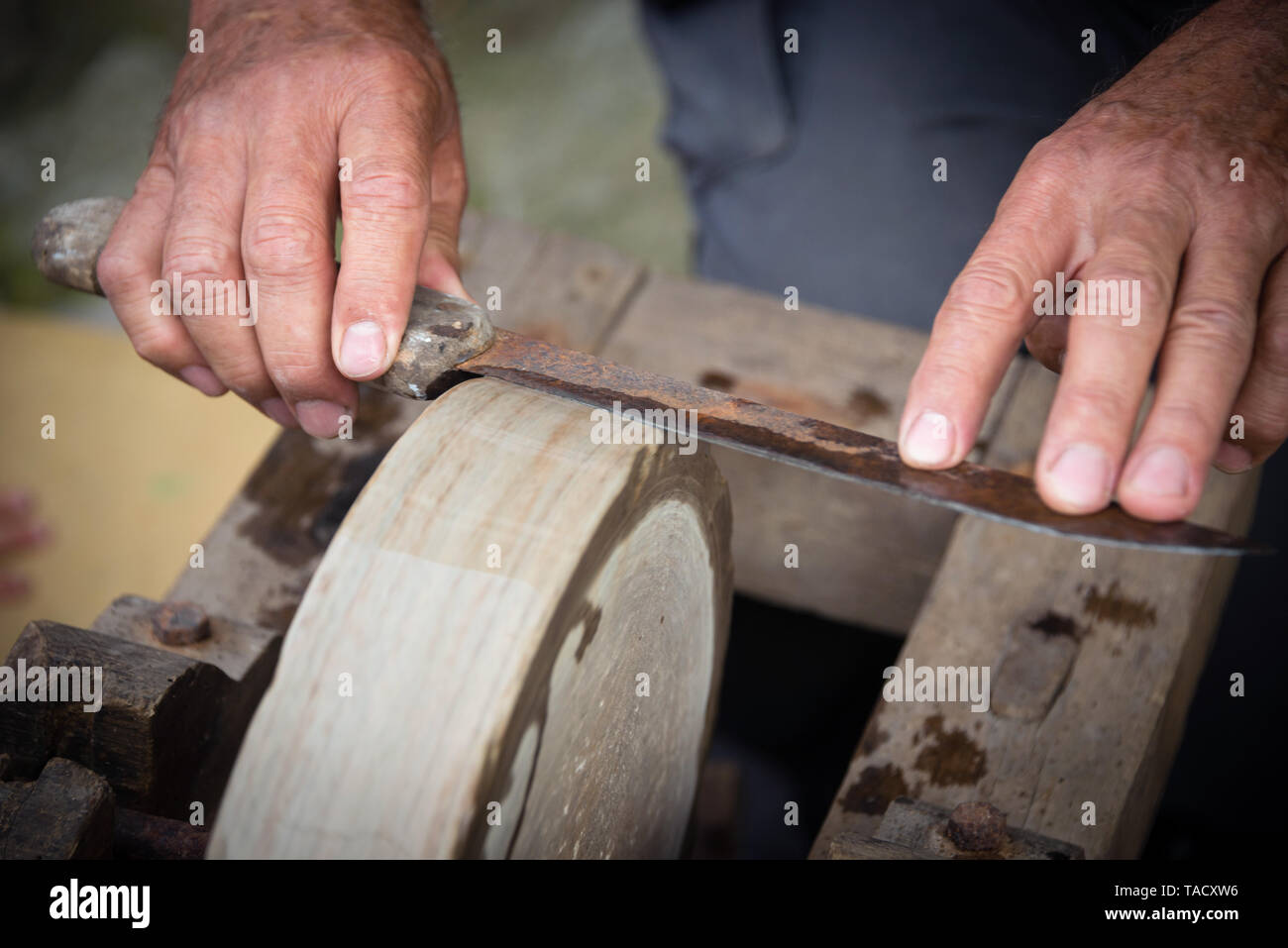 Sharpening knife on old grindstone wheel Stock Photo
