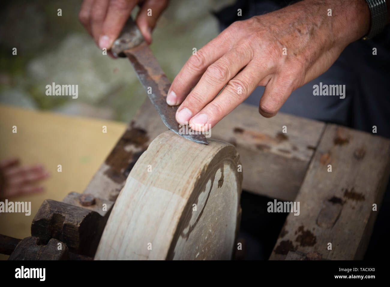 Sharpening knife on old grindstone wheel Stock Photo Alamy