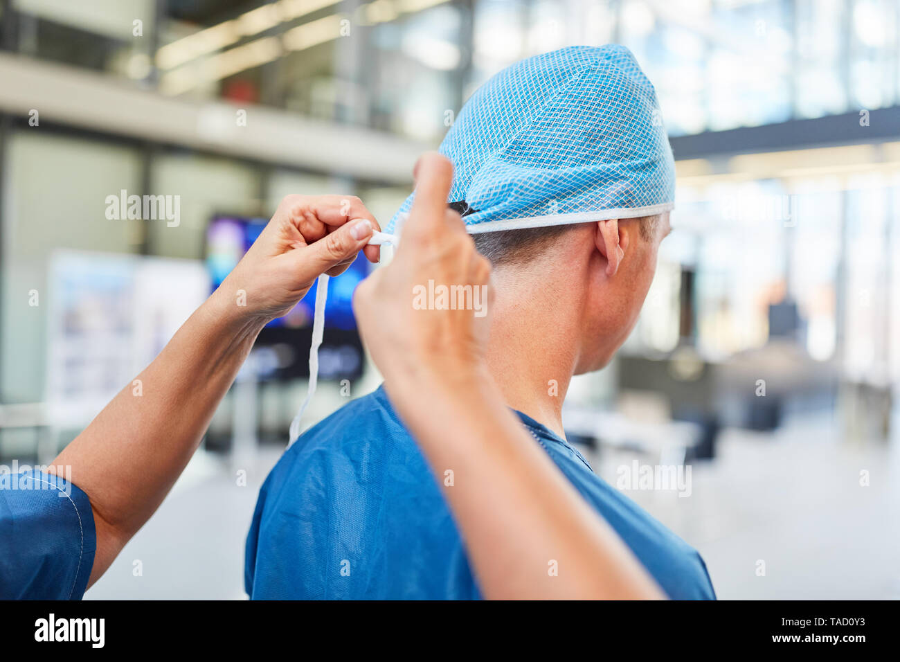 Doctor in the emergency room or intensive care unit with blue hood and surgical clothing Stock Photo