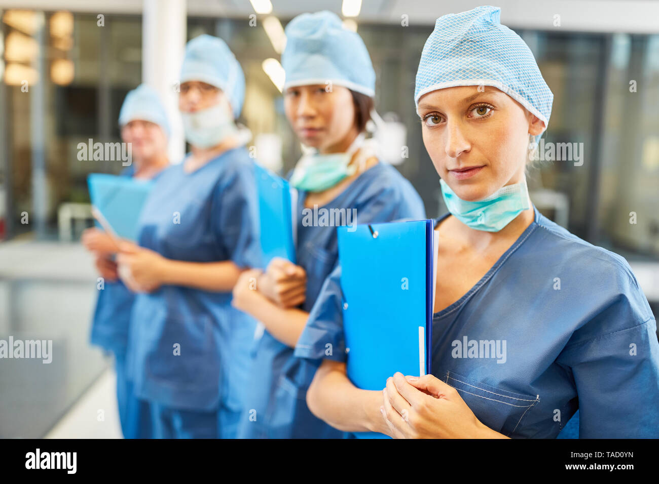 Young female doctor in blue surgical clothing together with colleagues as surgery team Stock Photo