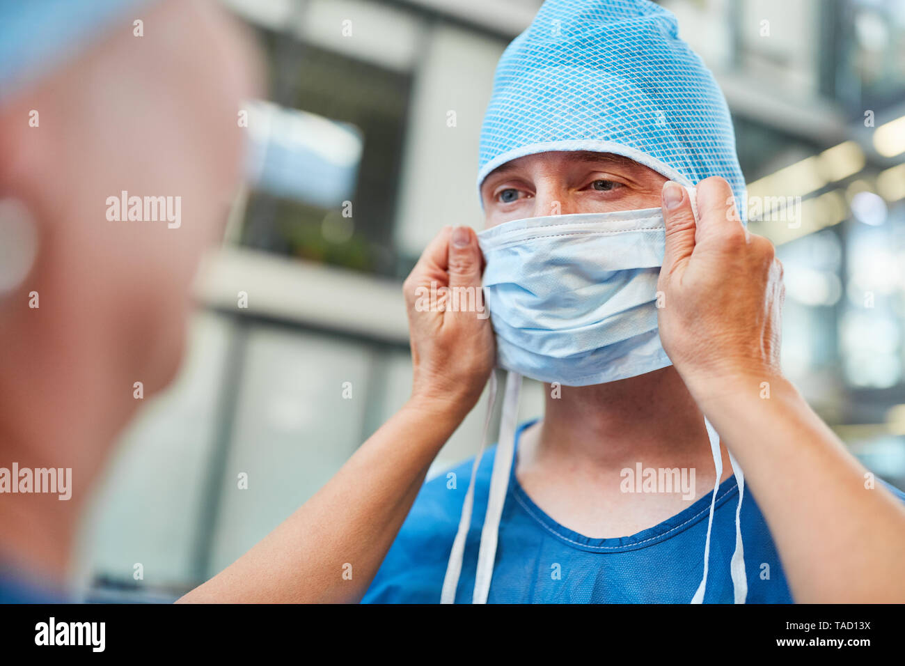 Doctor as a surgeon in blue surgical gown with surgical mask in emergency room of the clinic Stock Photo