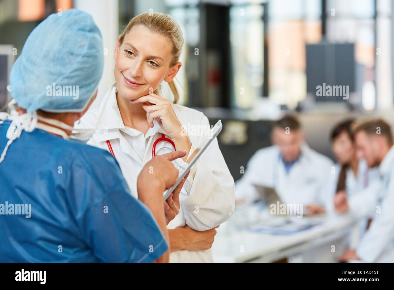 Surgeon in blue surgical gown and medical specialist discuss cooperation and therapy Stock Photo