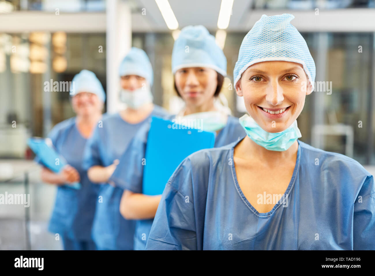 Smiling young surgeon in blue surgical clothing before her surgery or