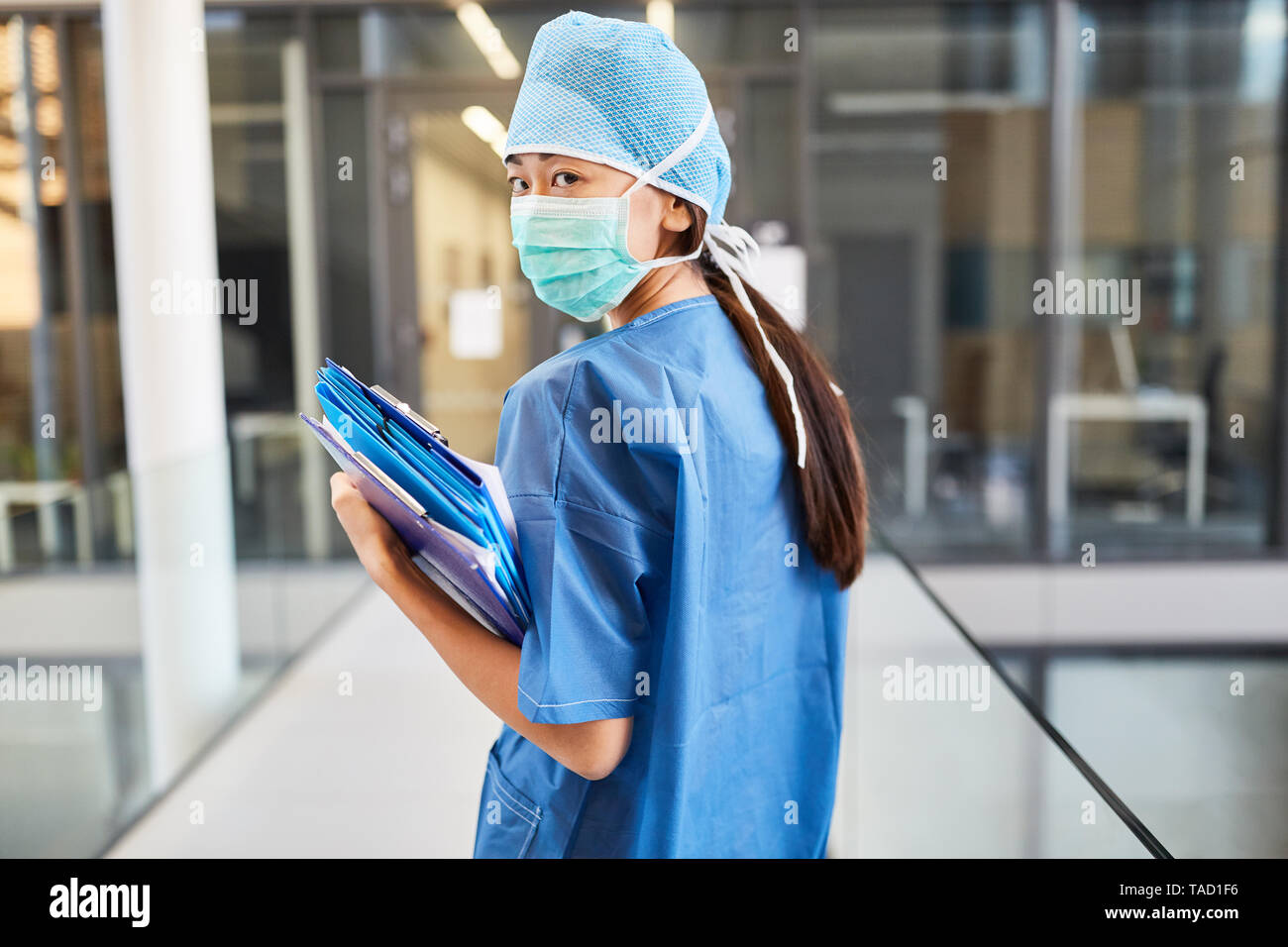 Young female doctor as a surgeon in blue surgical gown with patient files in the clinic Stock Photo