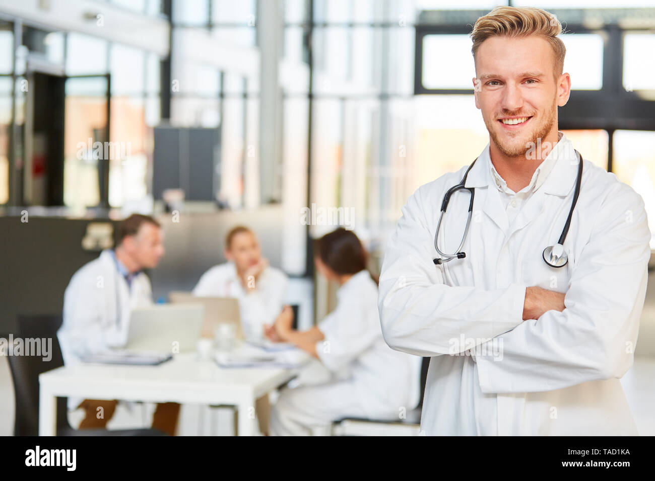 Young man as a smiling medical doctor in training in the hospital in a meeting Stock Photo