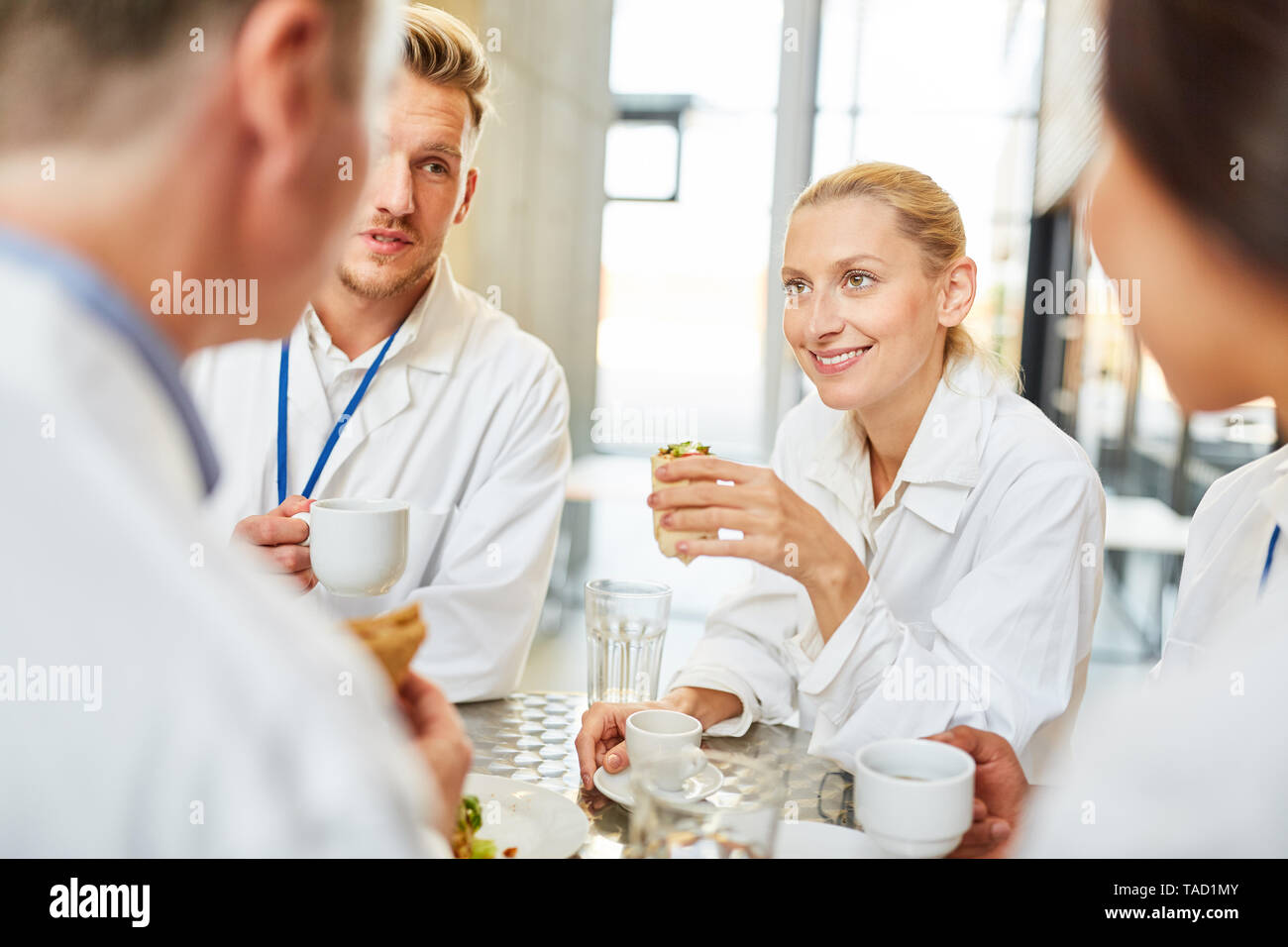 Group doctors in the hospital cafeteria drink coffee together and eat