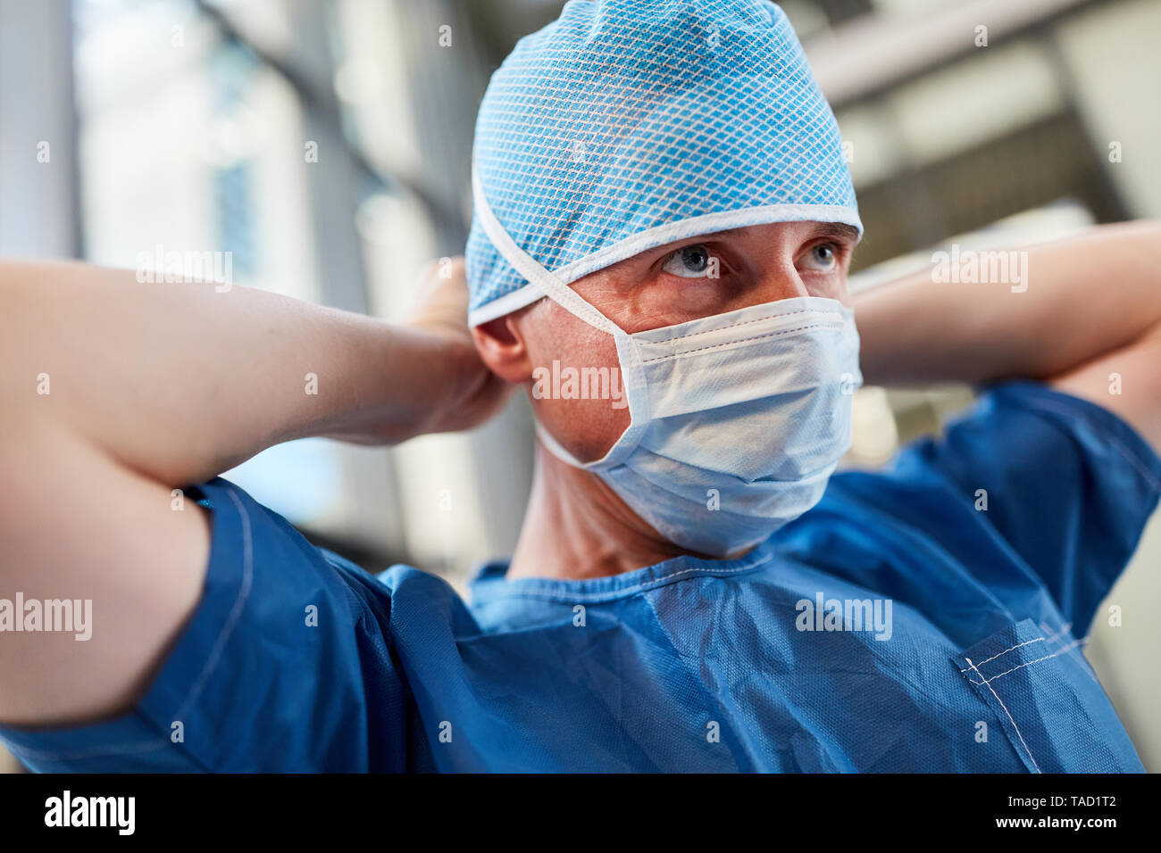 Surgeon in blue surgical gown with surgical mask and hood prepared for emergency service Stock Photo
