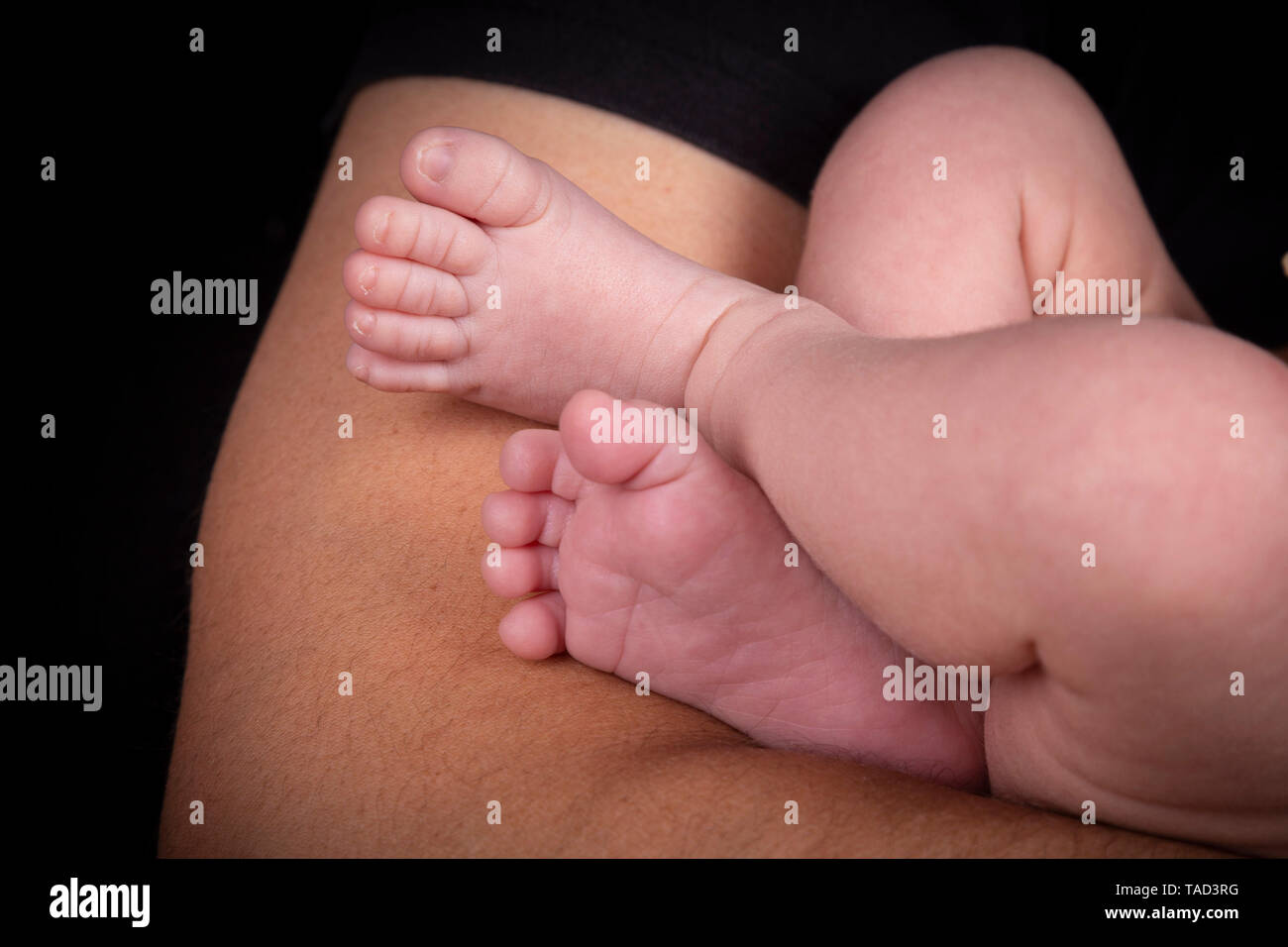 Baby feet collected by his father's arms Stock Photo