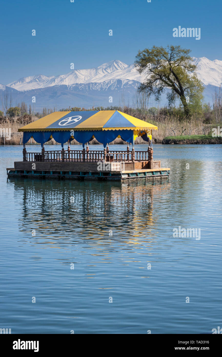 Lake with floating huts and snowy mountain view near Bishkek, Kyrgyzstan, Central Asia Stock Photo