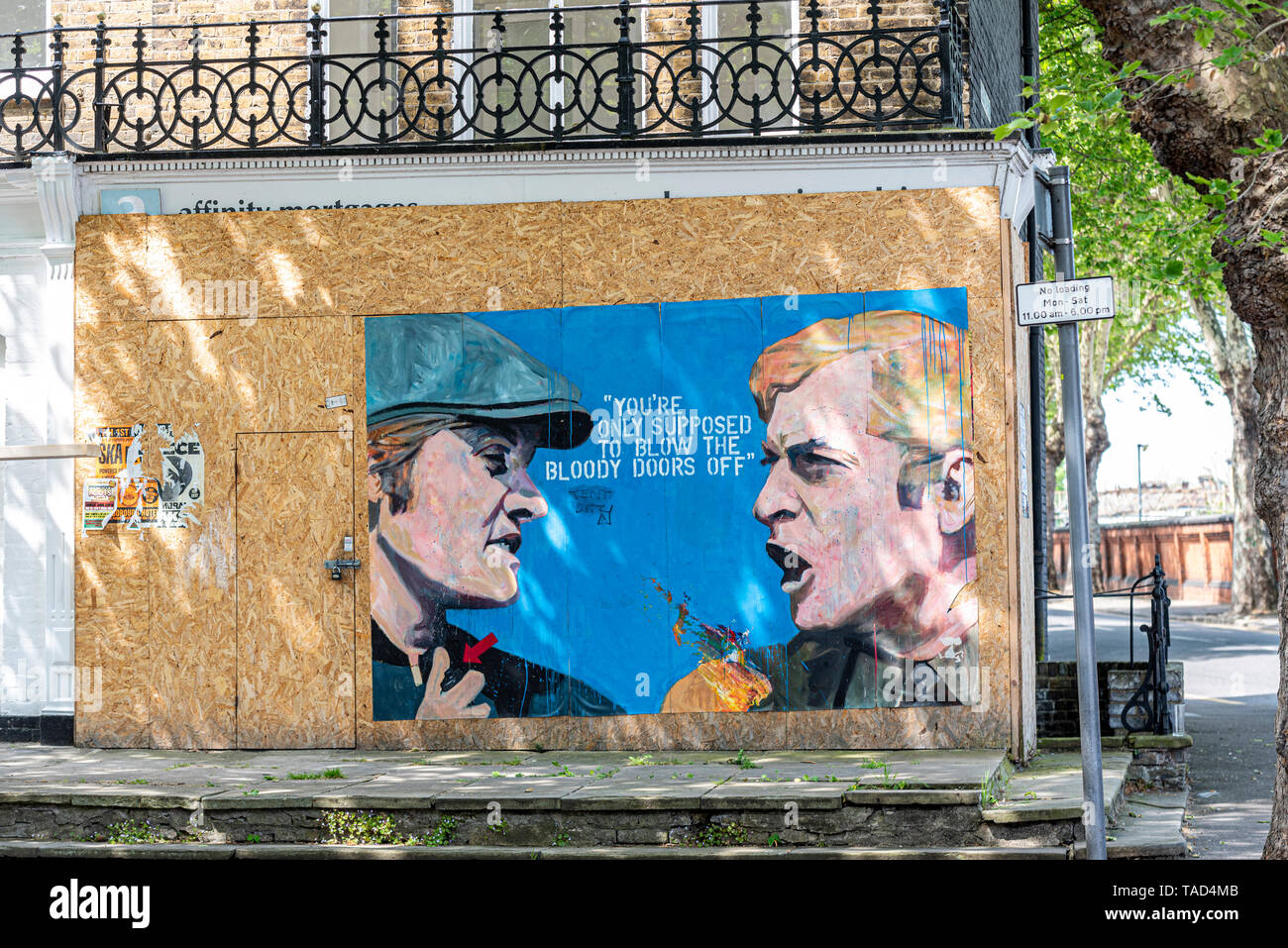 Graffiti painting on hoarding of boarded up vacant building property. Scene from Italian Job, Michael Caine only supposed to blow the doors off quote Stock Photo