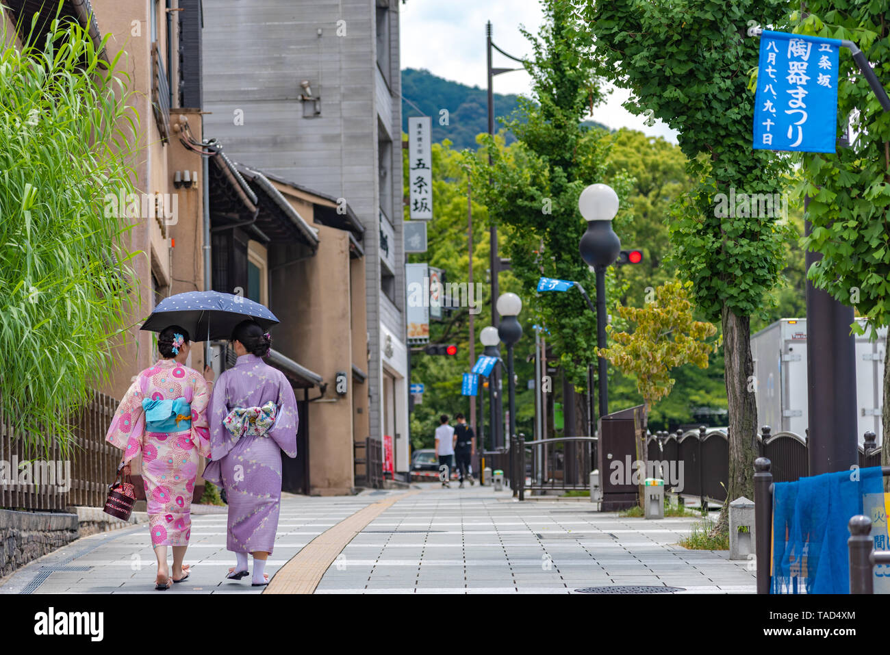 Women wearing traditional dress (kimono) walking on street around the traditional buildings in Kyoto, Japan Stock Photo