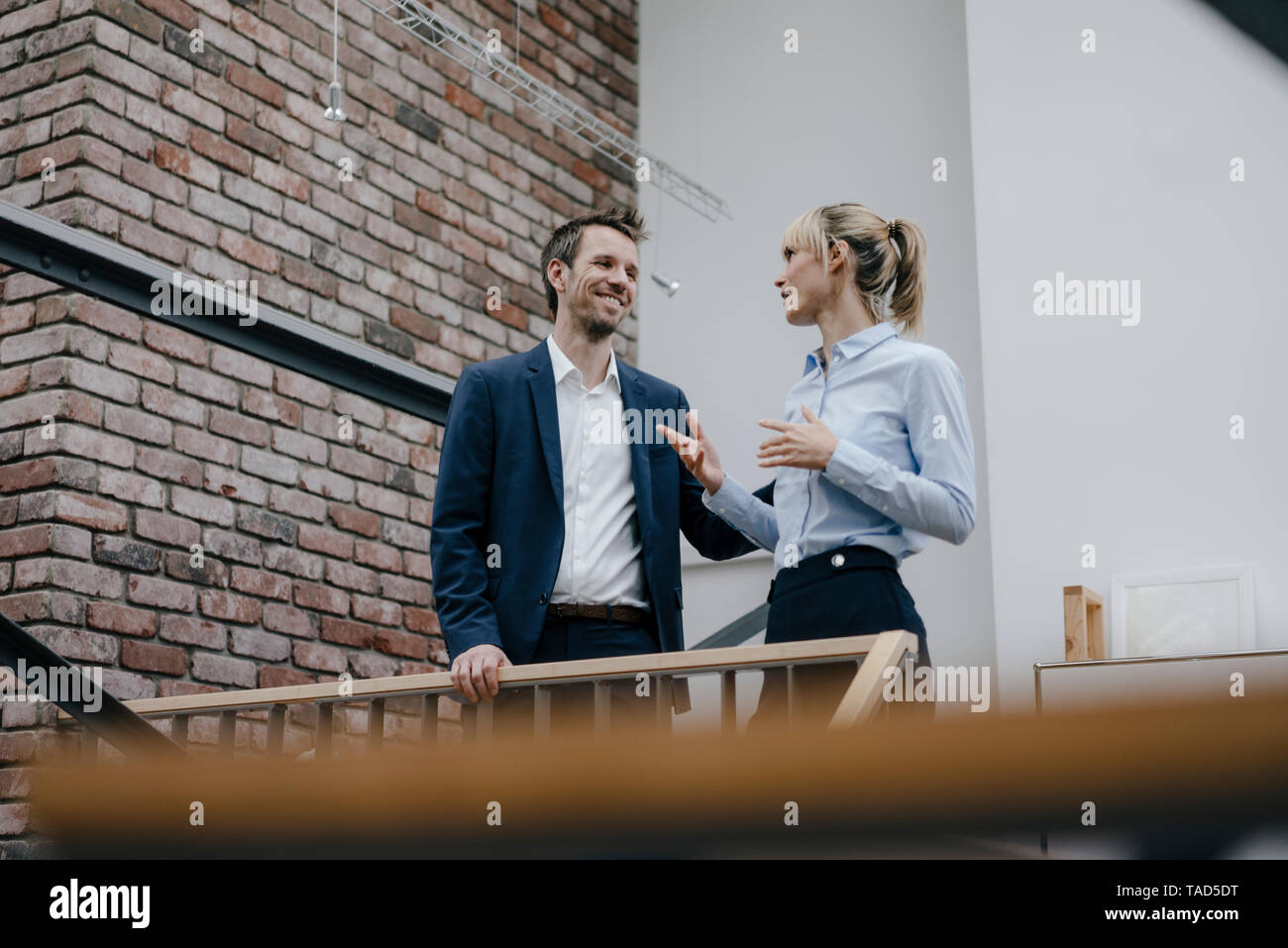 Businessman and woman standing in office building, discussing Stock Photo
