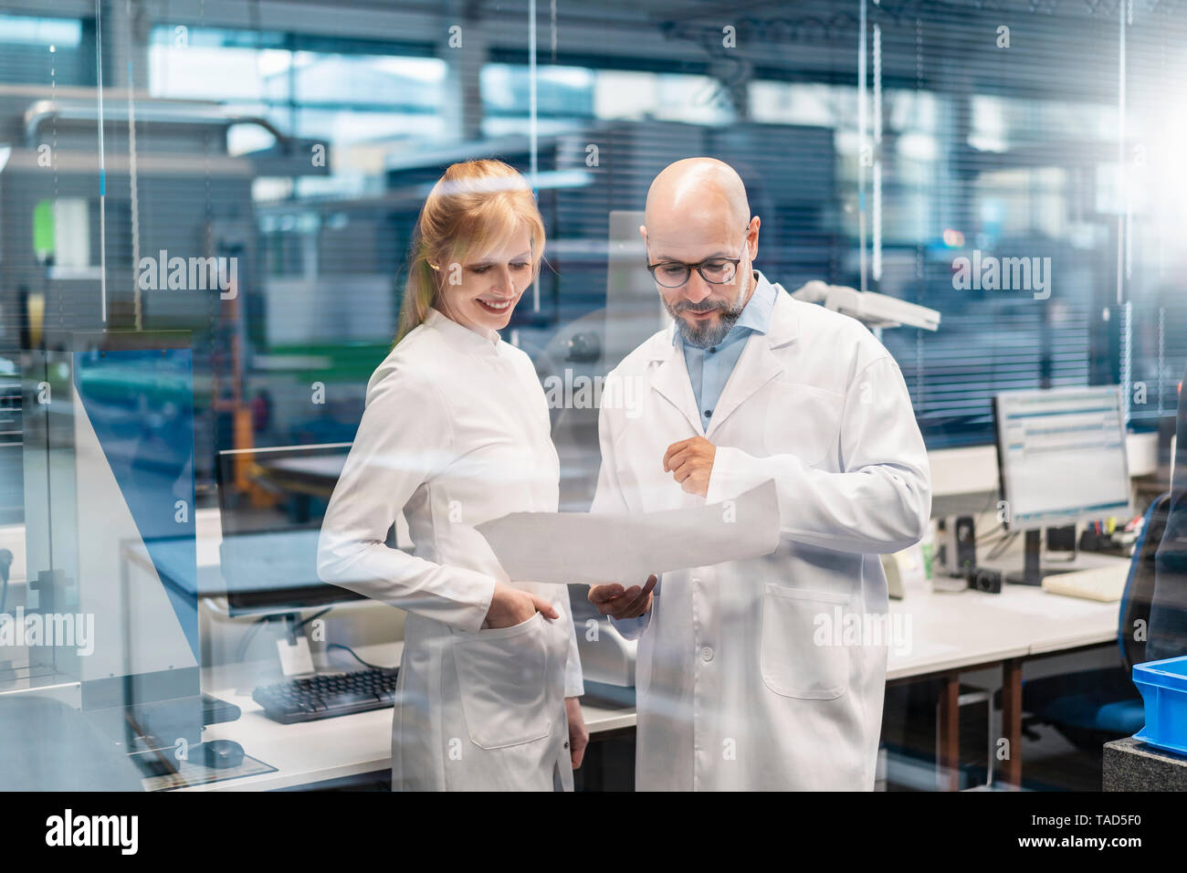 Two technicians wearing lab coats looking at plan Stock Photo