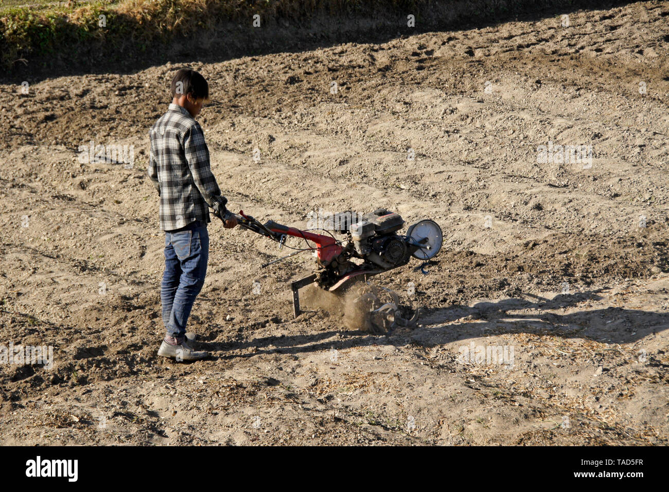 Farmer tilling soil with gas-powered rototiller, Mulpani, Kathmandu Valley, Nepal Stock Photo
