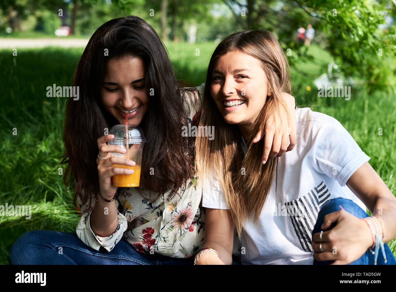 Portrait of two happy young women drinking juice at a picnic in park Stock Photo