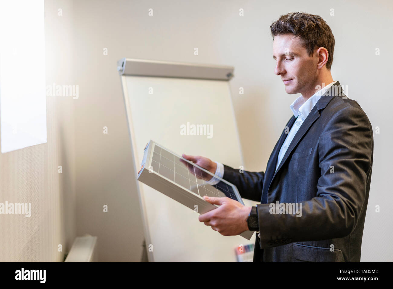 Businessman holding solar cell in office Stock Photo