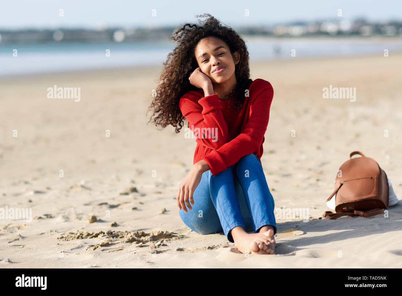 Portrait of smiling young woman sitting on the beach Stock Photo - Alamy