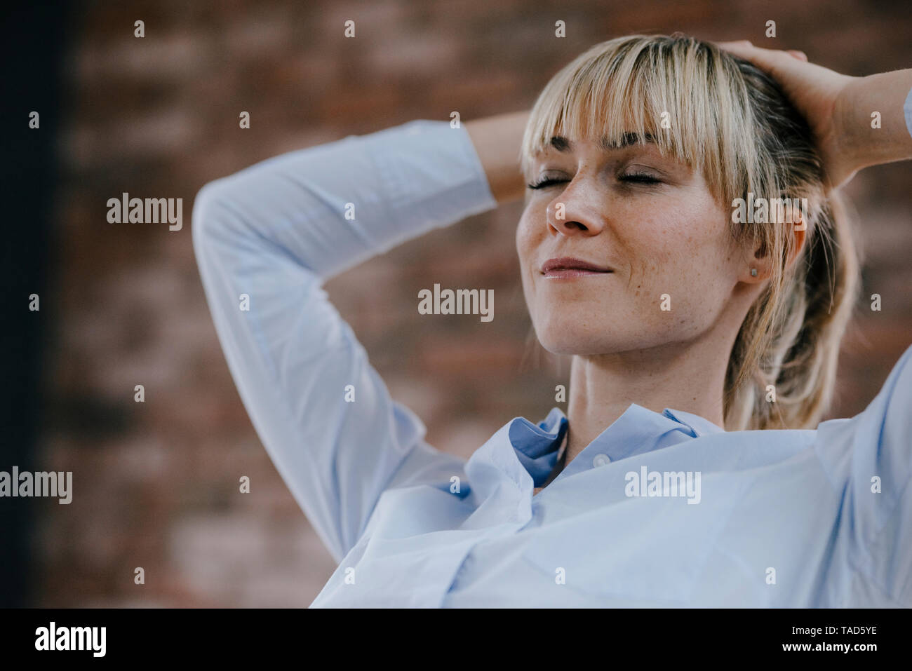 Businesswoman relaxing in office, with hands behind head Stock Photo