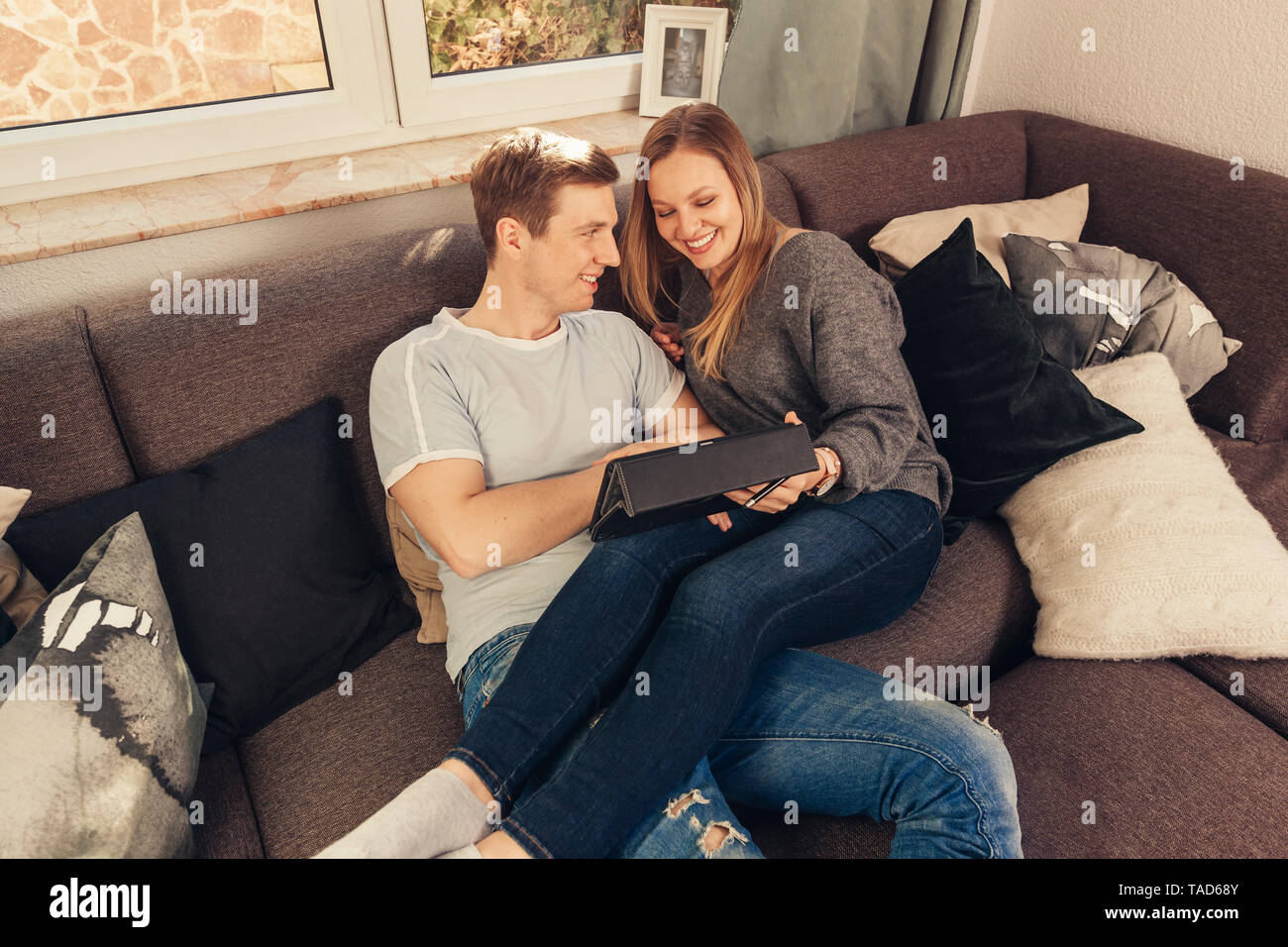 Young couple relaxing on sofa and using a tablet Stock Photo