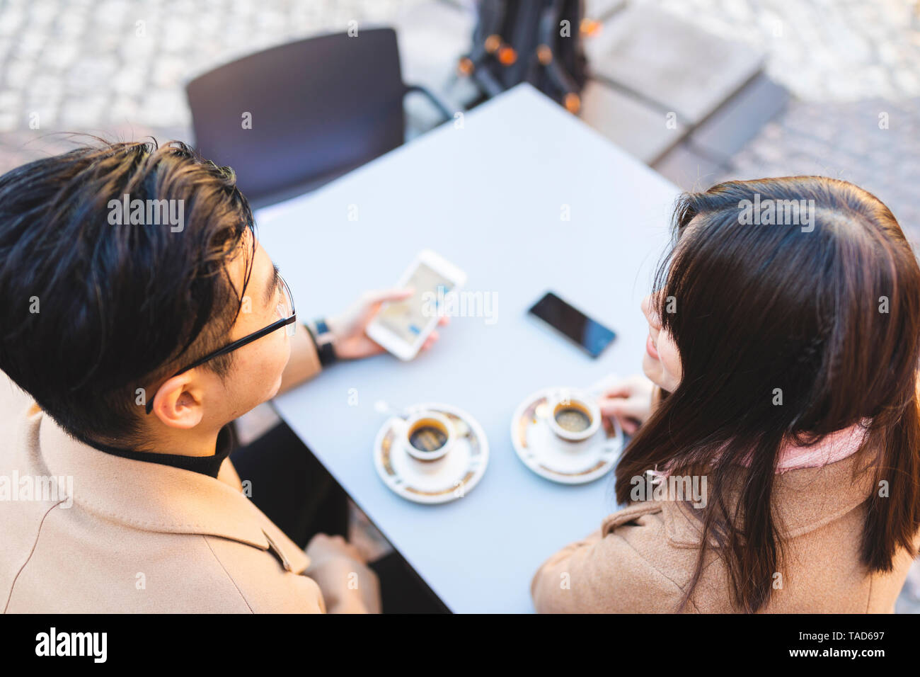 Young couple with cell phone in a street cafe Stock Photo