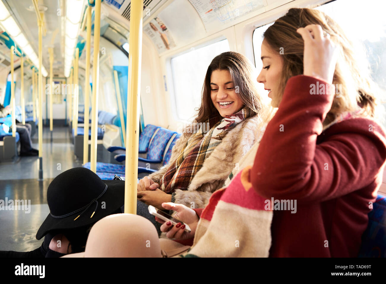 UK, London, two happy women in underground train using cell phone Stock Photo