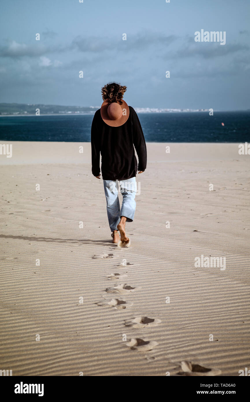 Young man walking away in the dunes, rear view Stock Photo