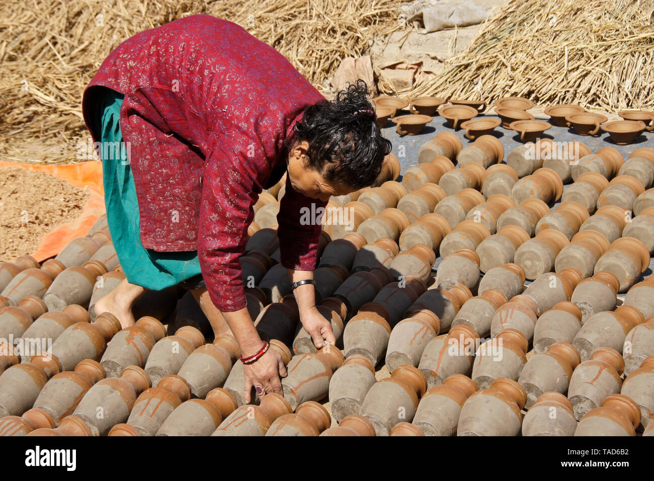 Woman turning clay pots as they sun-dry in Kumale Tol (Potters' Square, Pottery Square), Bhaktapur, Kathmandu Valley, Nepal Stock Photo