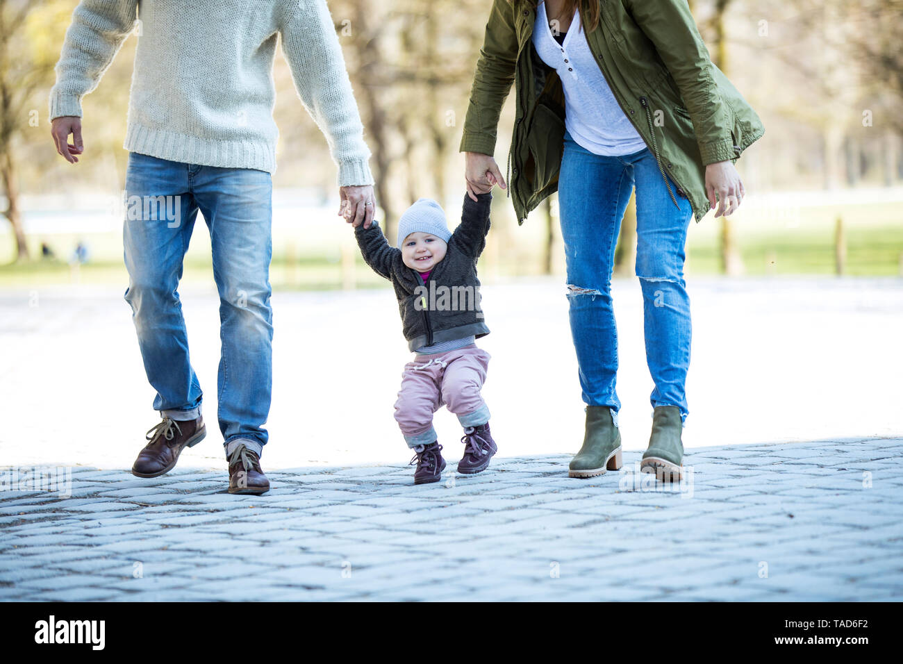 Portrait of happy girl walking hand in hand with parents Stock Photo