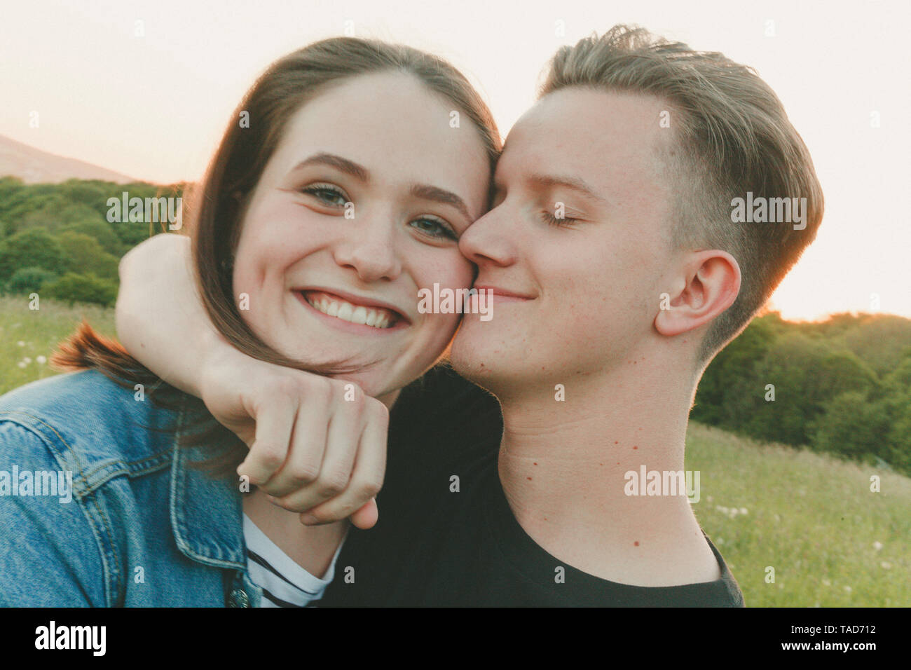 Portrait of happy teenage girl with boyfriend in nature in the evening Stock Photo