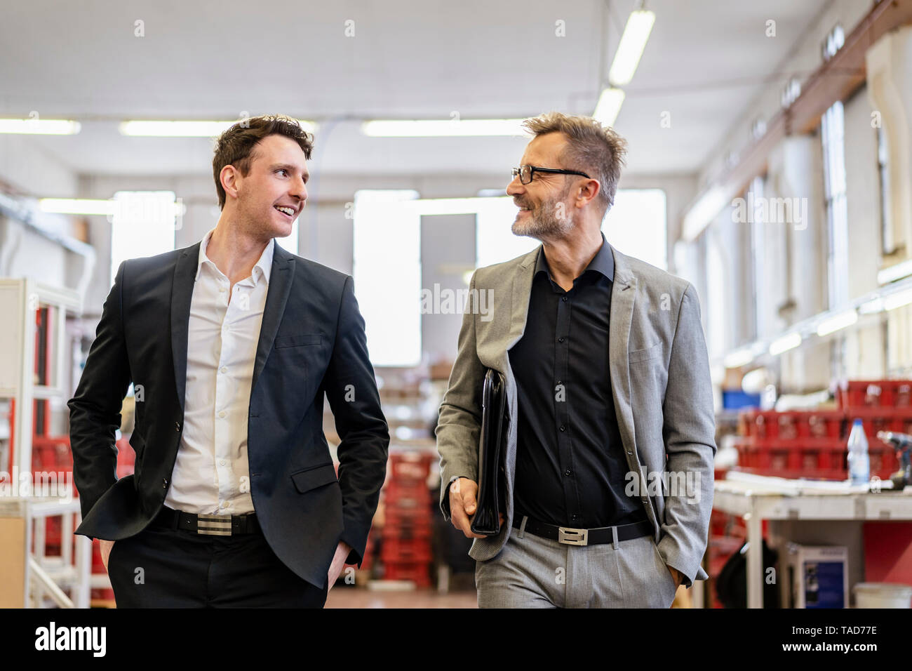 Two smiling businessmen talking in a factory Stock Photo - Alamy