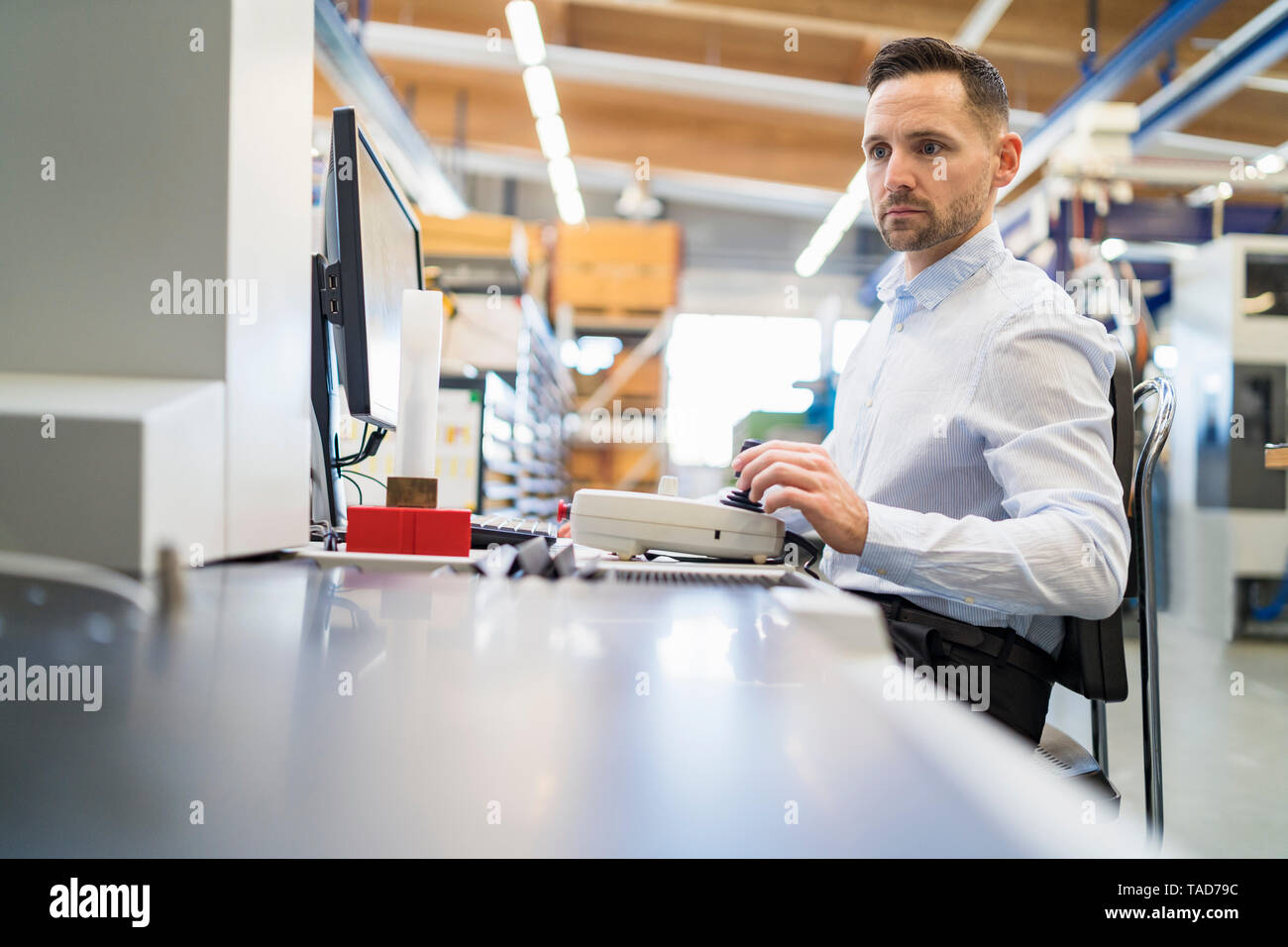 Man operating machine at desk in a factory Stock Photo