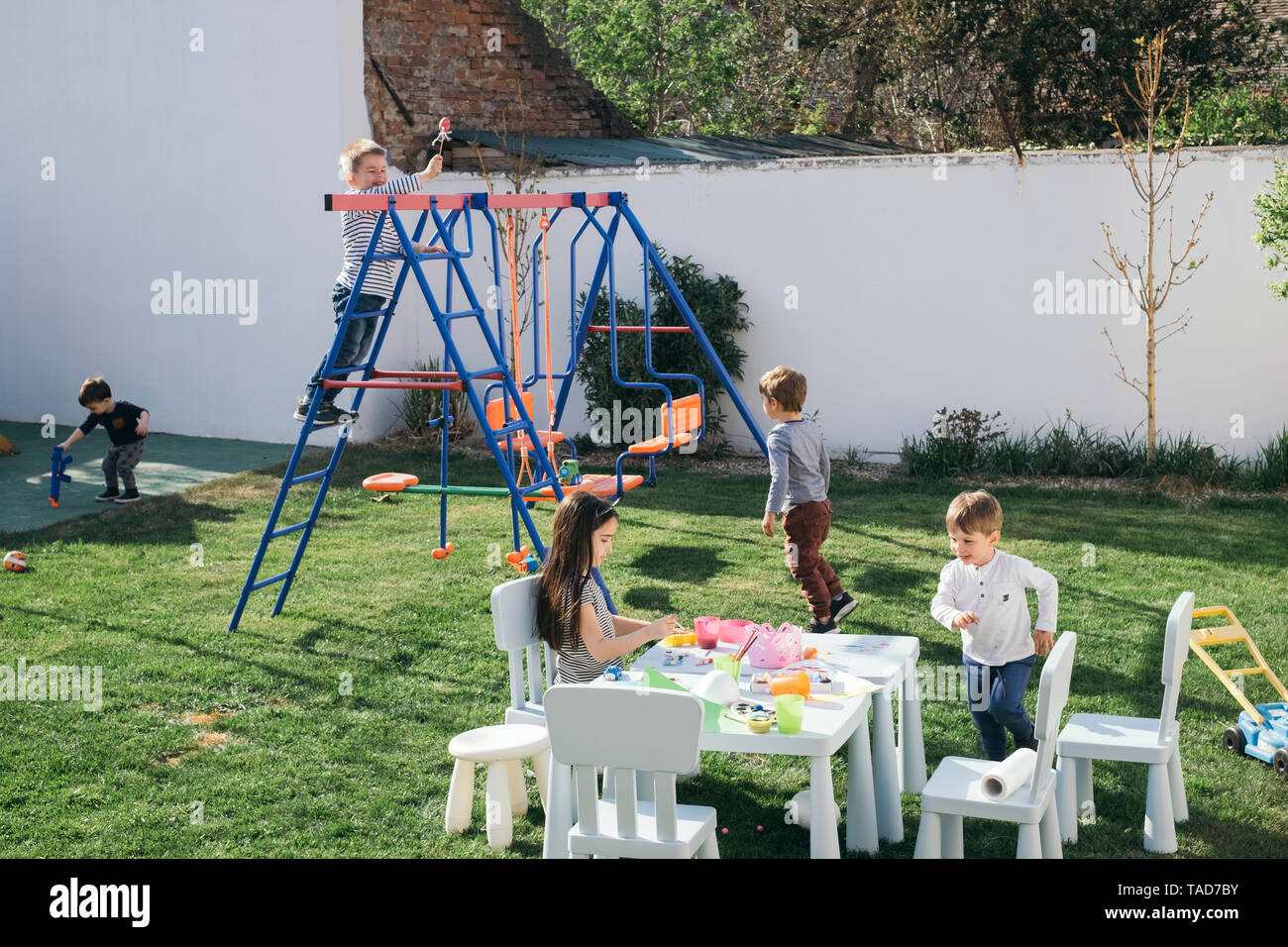 Kids playing in a garden, paining Easter eggs, climbing on swing Stock Photo