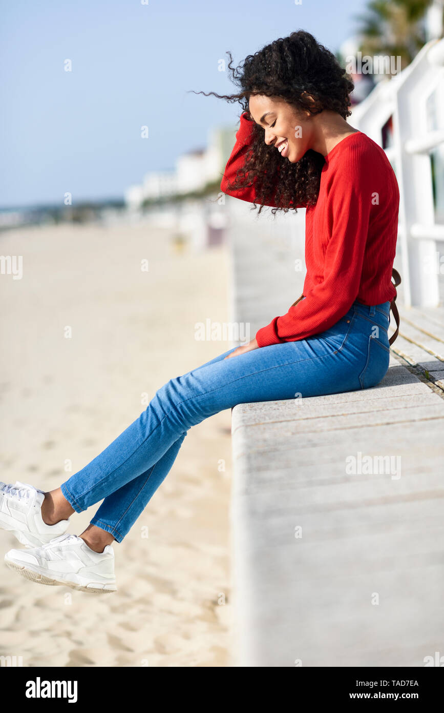 Happy young woman sitting on beach promenade Stock Photo - Alamy