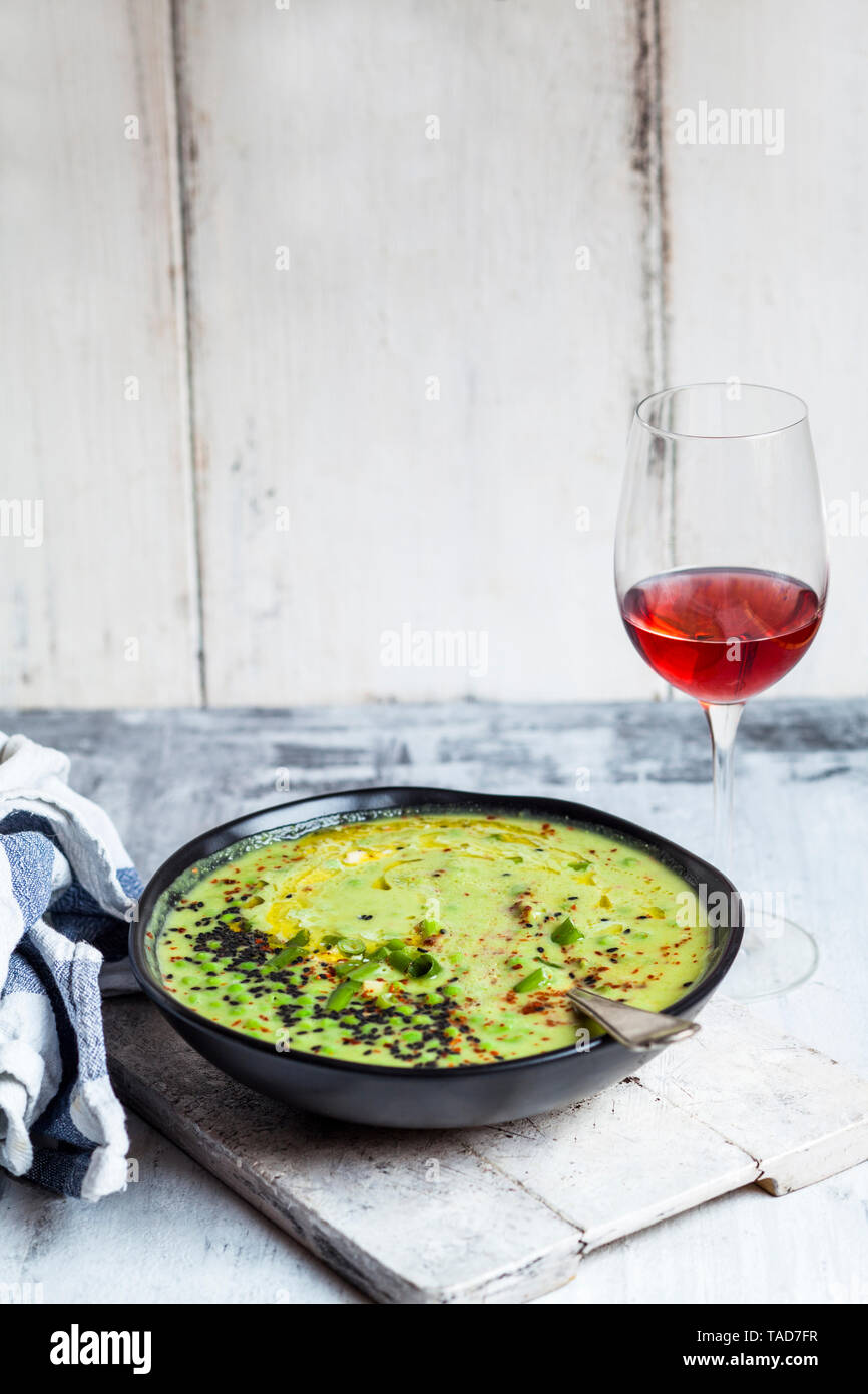 Bowl of Fresh green pea soup with spring onions and a glass of blush Wine Stock Photo