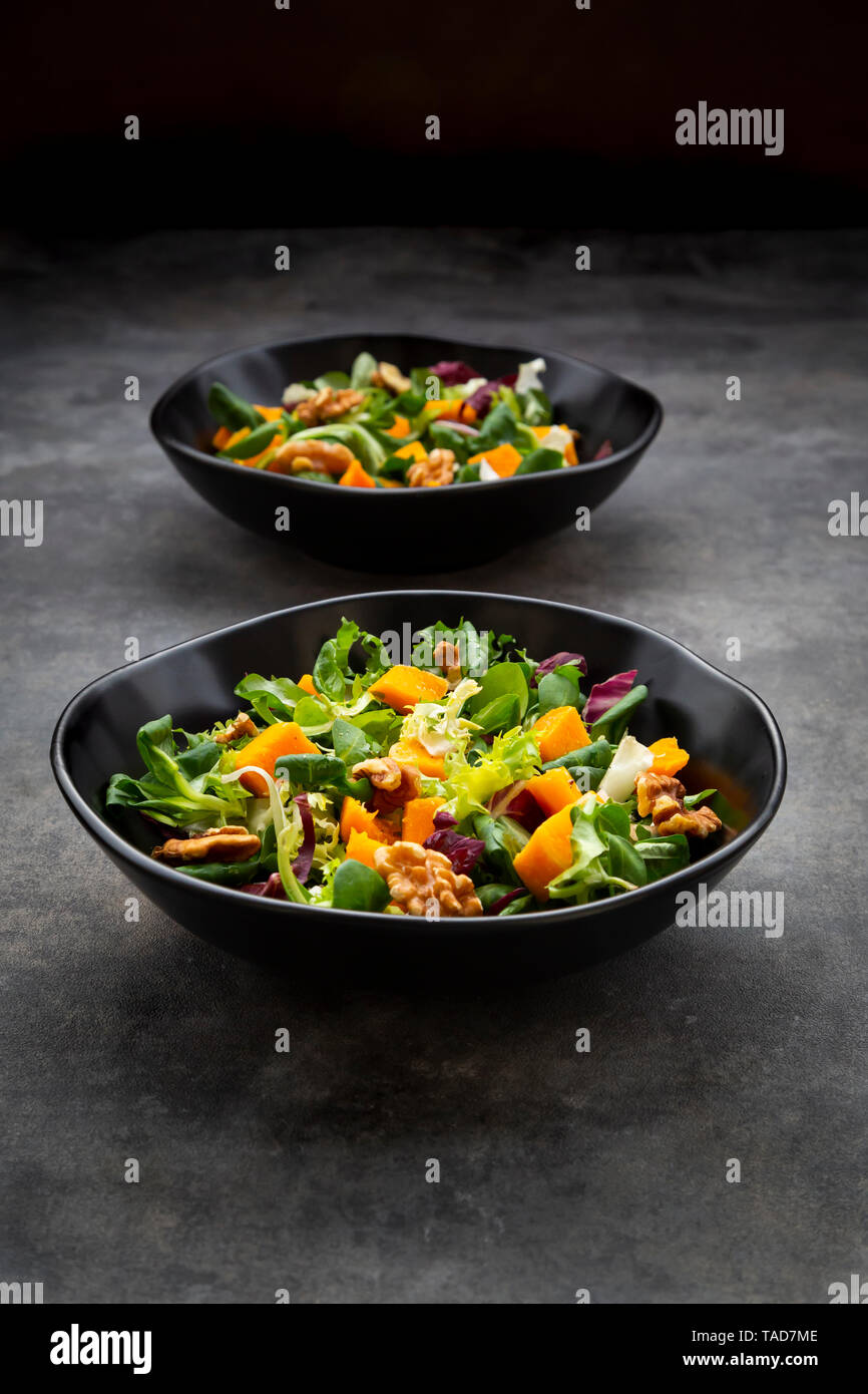 Two bowls of mixed green salad with hokkaido pumpkin and walnuts Stock