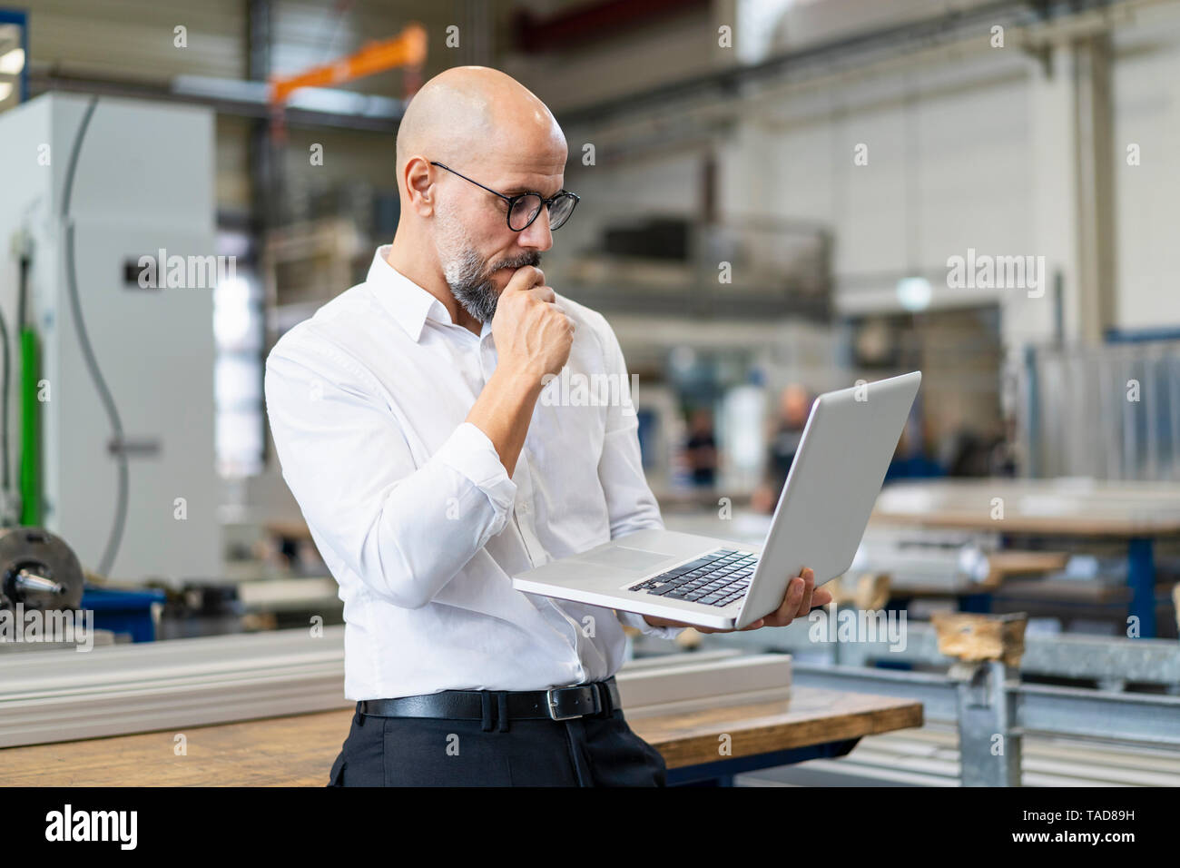 Focused businessman using laptop in factory Stock Photo
