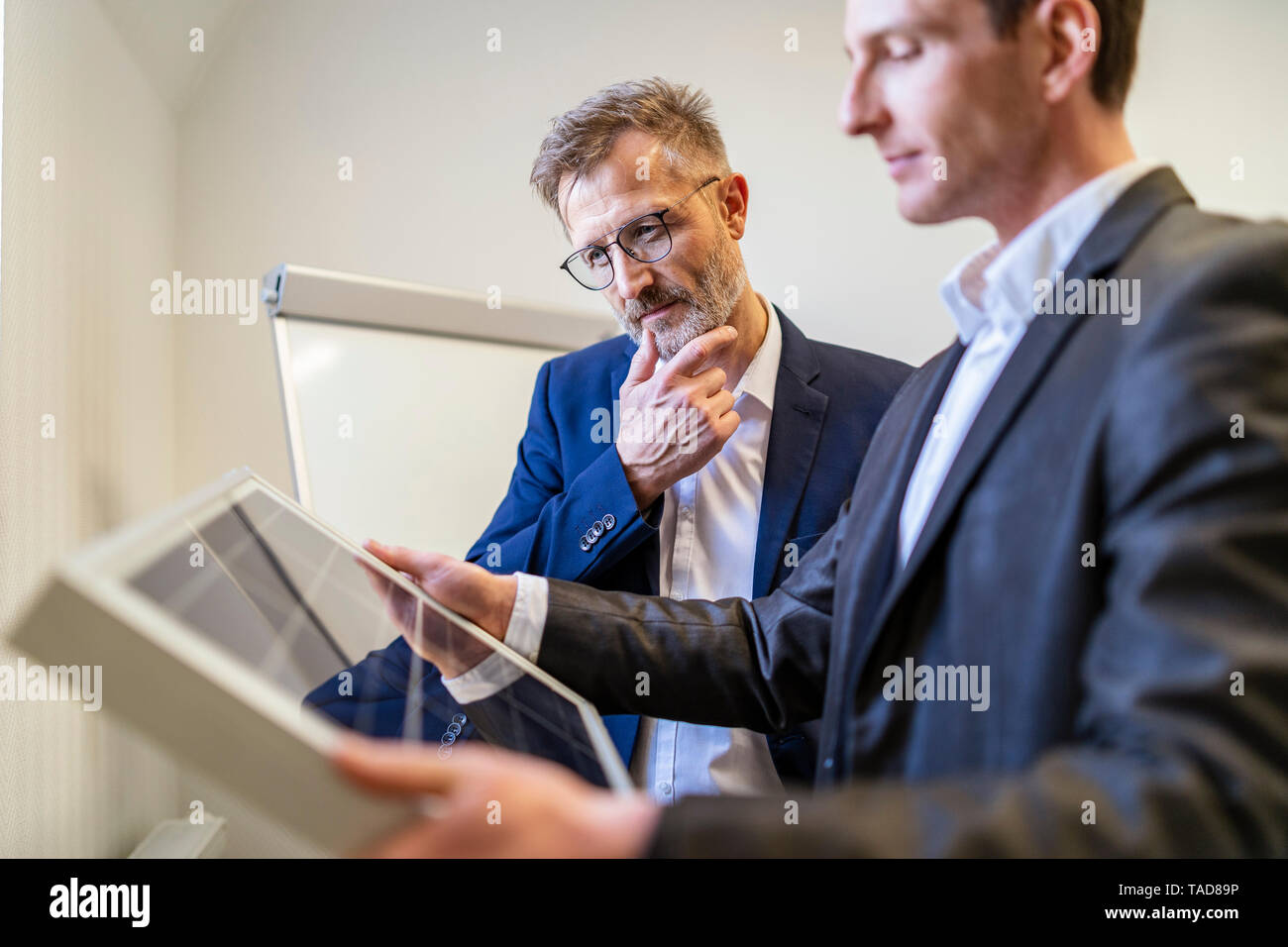 Two businessmen in office looking at solar cell Stock Photo