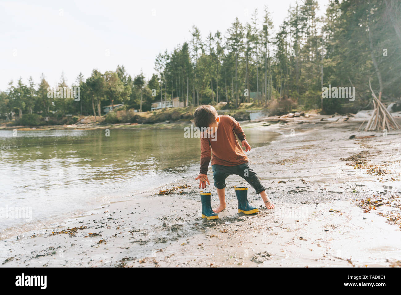 Boy playing on a the beach, walking barefoot in the mud Stock Photo