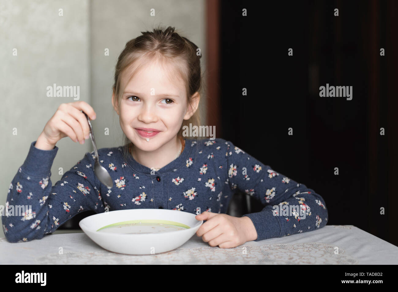 Portrait of smiling little girl eating oat meal Stock Photo