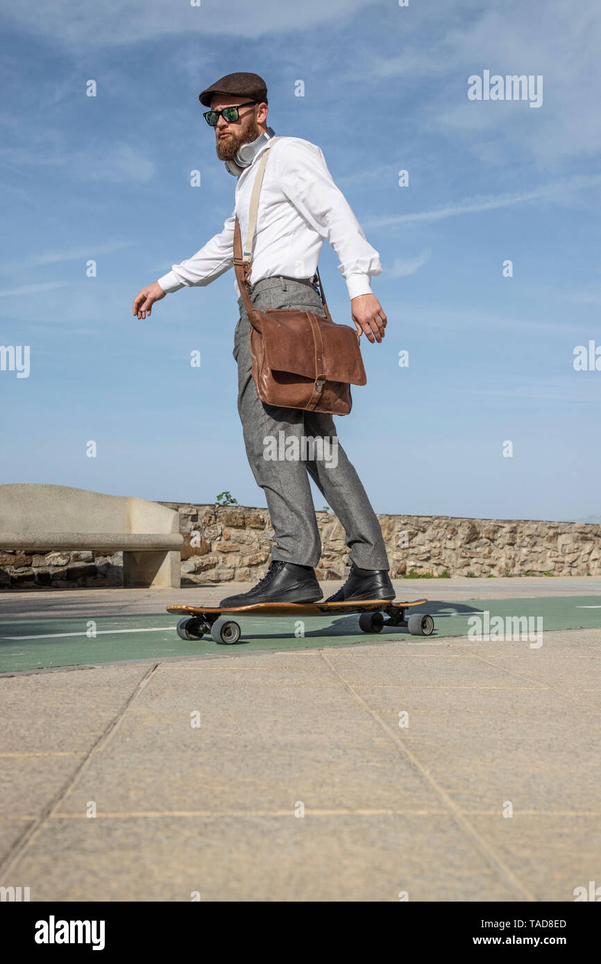 Bearded man with leather bag on longboard Stock Photo