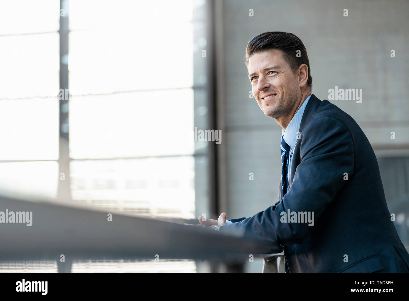 Smiling businessman leaning on railing Stock Photo