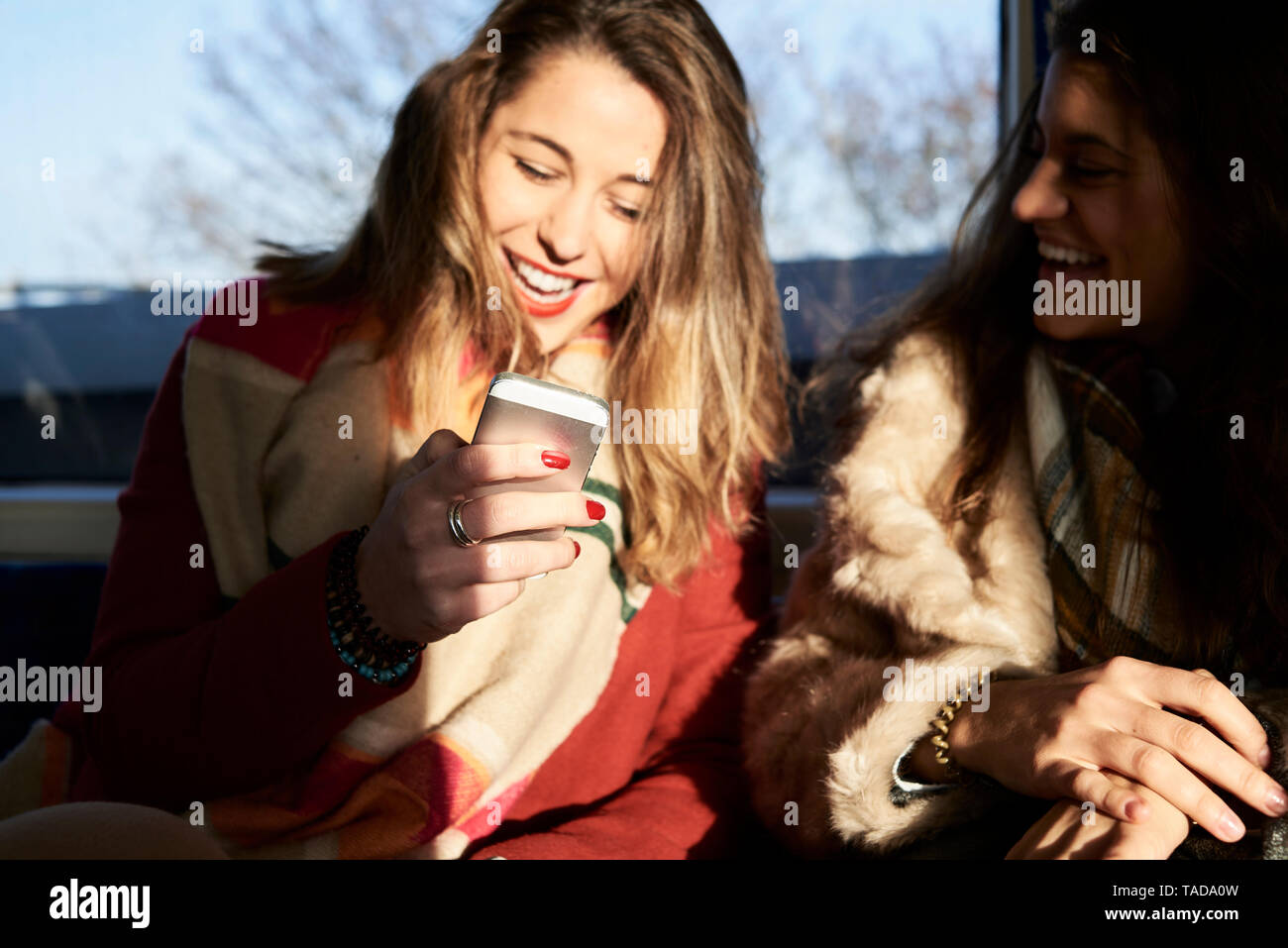 UK, London, two happy women in underground train using cell phone Stock Photo