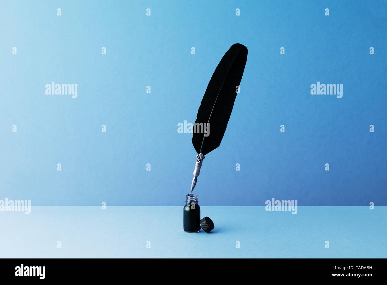 Quill pen and inkwell over blue background Stock Photo