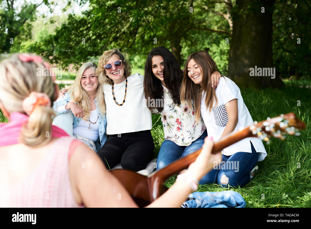 Group of women with guitar having fun at a picnic in park Stock Photo